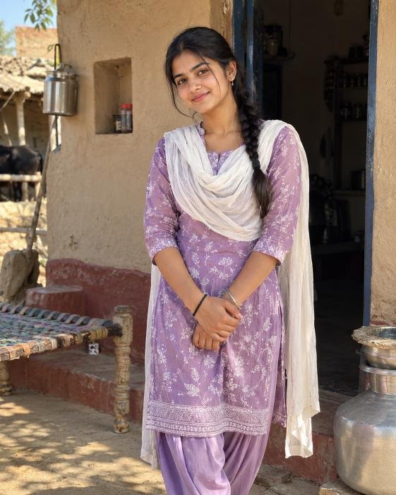 Young woman in traditional suit outside a village home